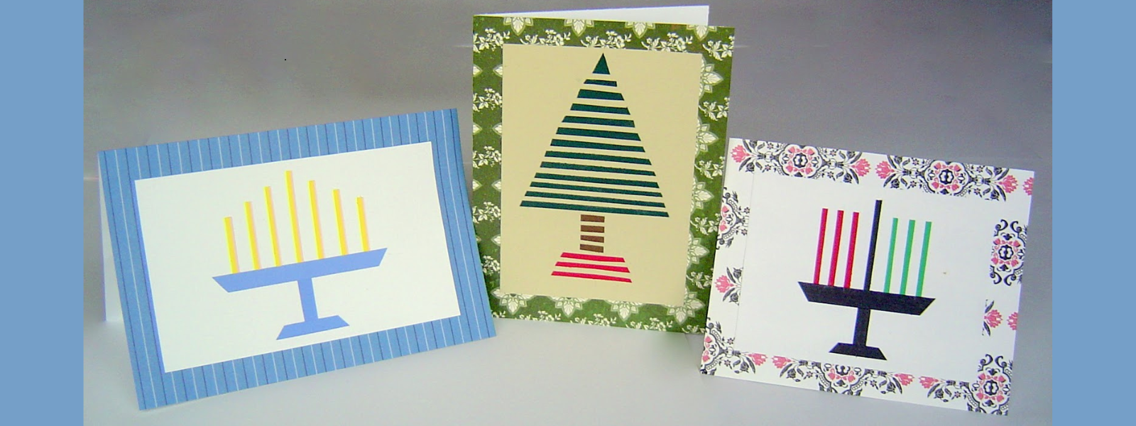 Three holiday cards are displayed. The first shows a blue menorah, the second has a striped Christmas tree, and the third features a menorah with colorful candles.