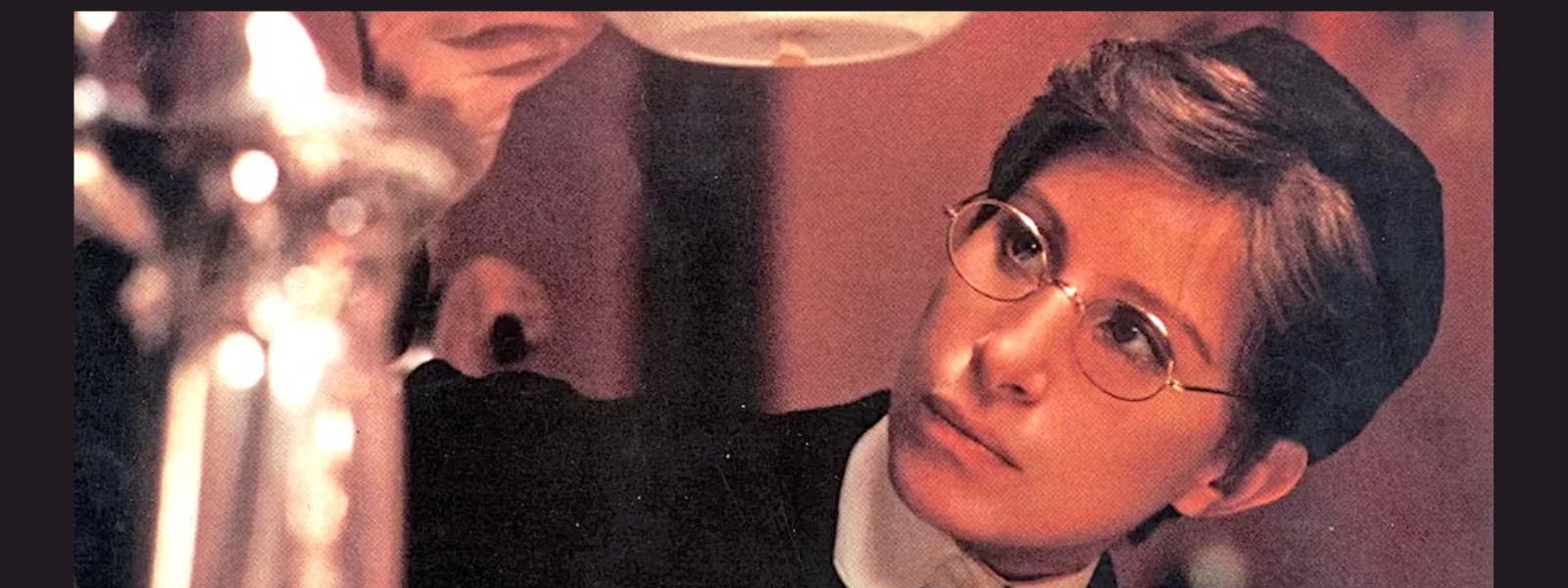 A person wearing glasses and a dark cap intently examines a white object, possibly a dish, in warm lighting. The scene conveys focus and curiosity.