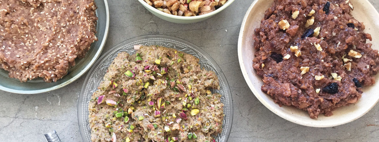 A variety of Persian sweets on a table: bowls of nutty and fruit-studded halva, and other sweet pastes, creating a warm, inviting atmosphere.